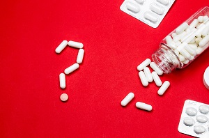 Blue Pills and Pill Bottle in the shape of a Question Mark.