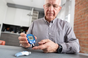 Senior man checking blood sugar level at home