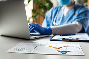 doctor typing on computer with graphs