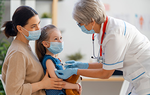 doctor vaccinating child with mother