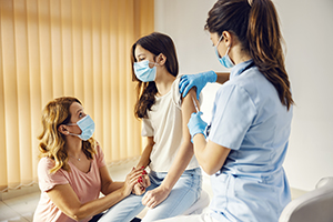 female doctor giving girl a shot