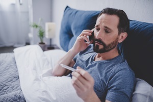 sick man holding thermometer